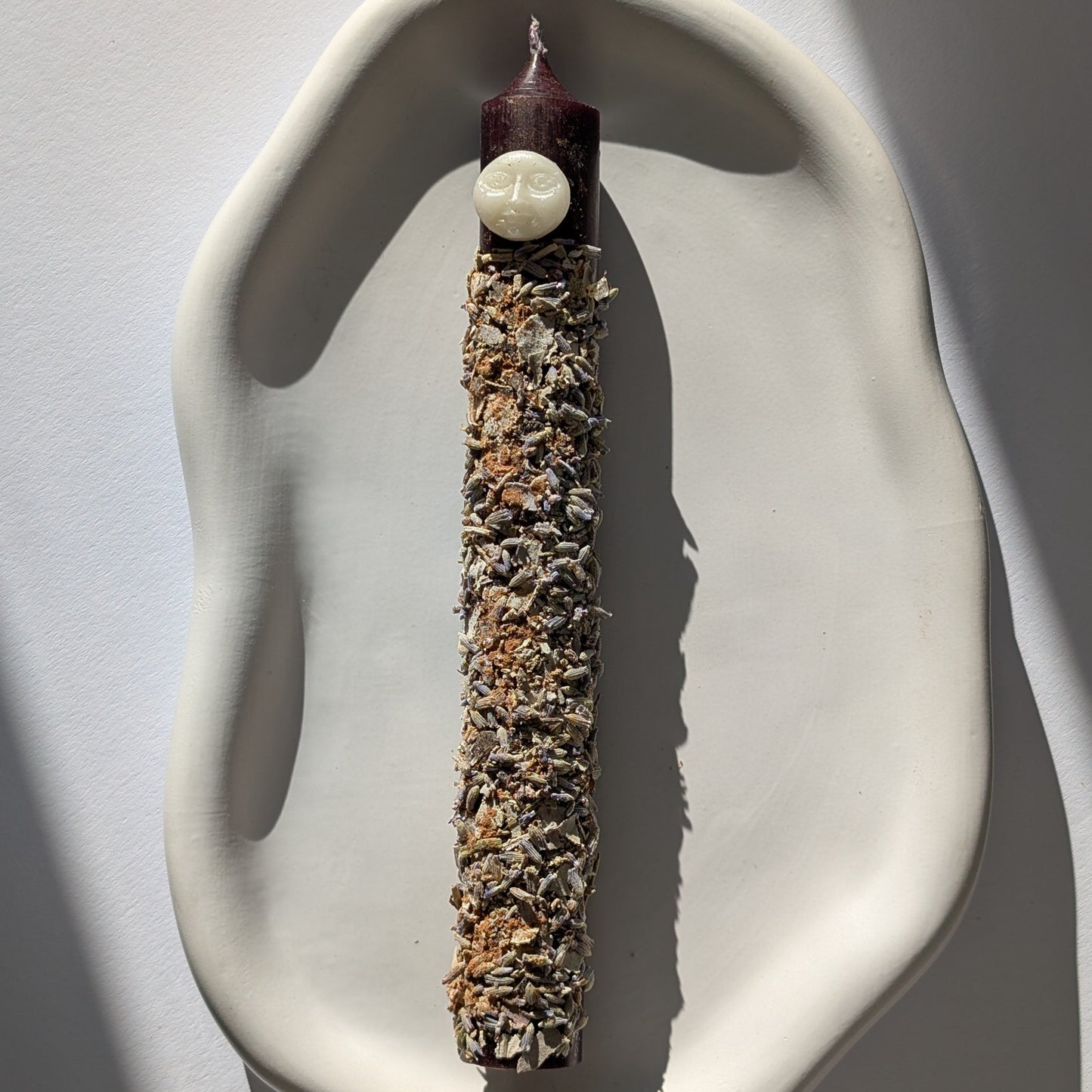 Handgegossene Vollmond Ritualkerze "Lunar Abundance" mit Kräutern in einem Glasgefäß.