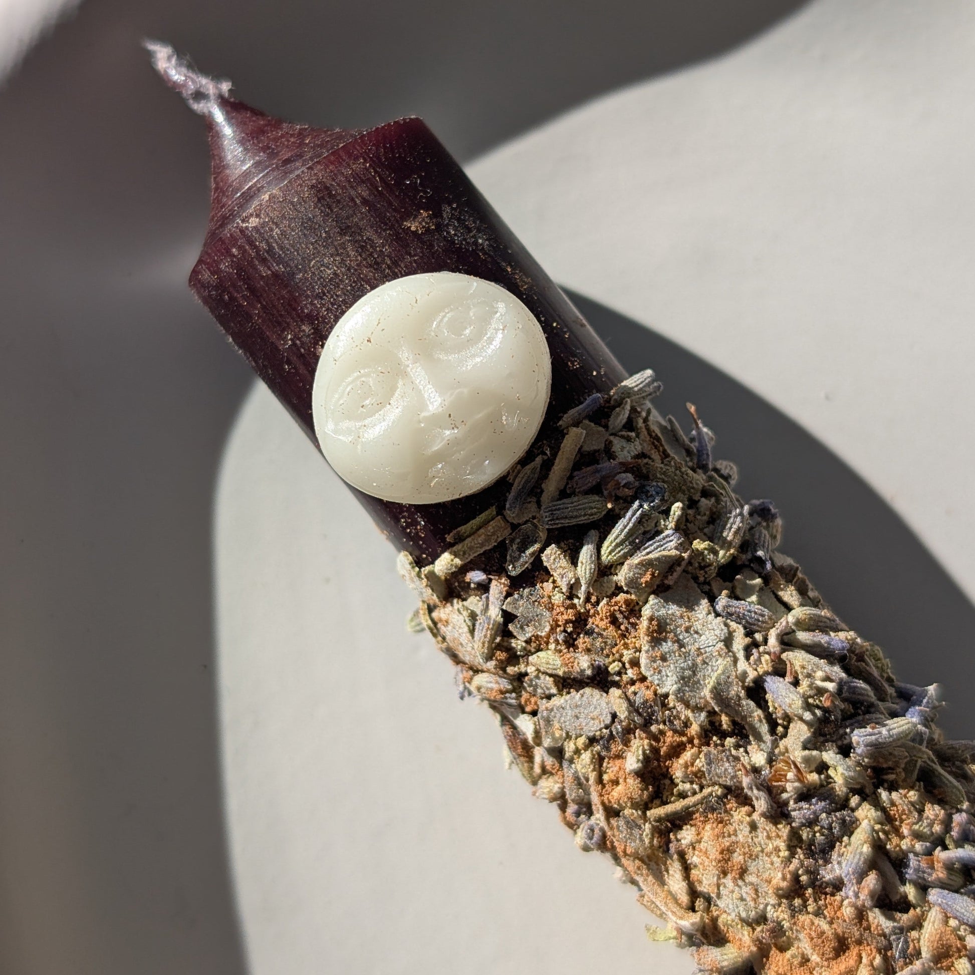 Handgegossene Vollmond Ritualkerze "Lunar Abundance" mit Kräutern in einem Glasgefäß.