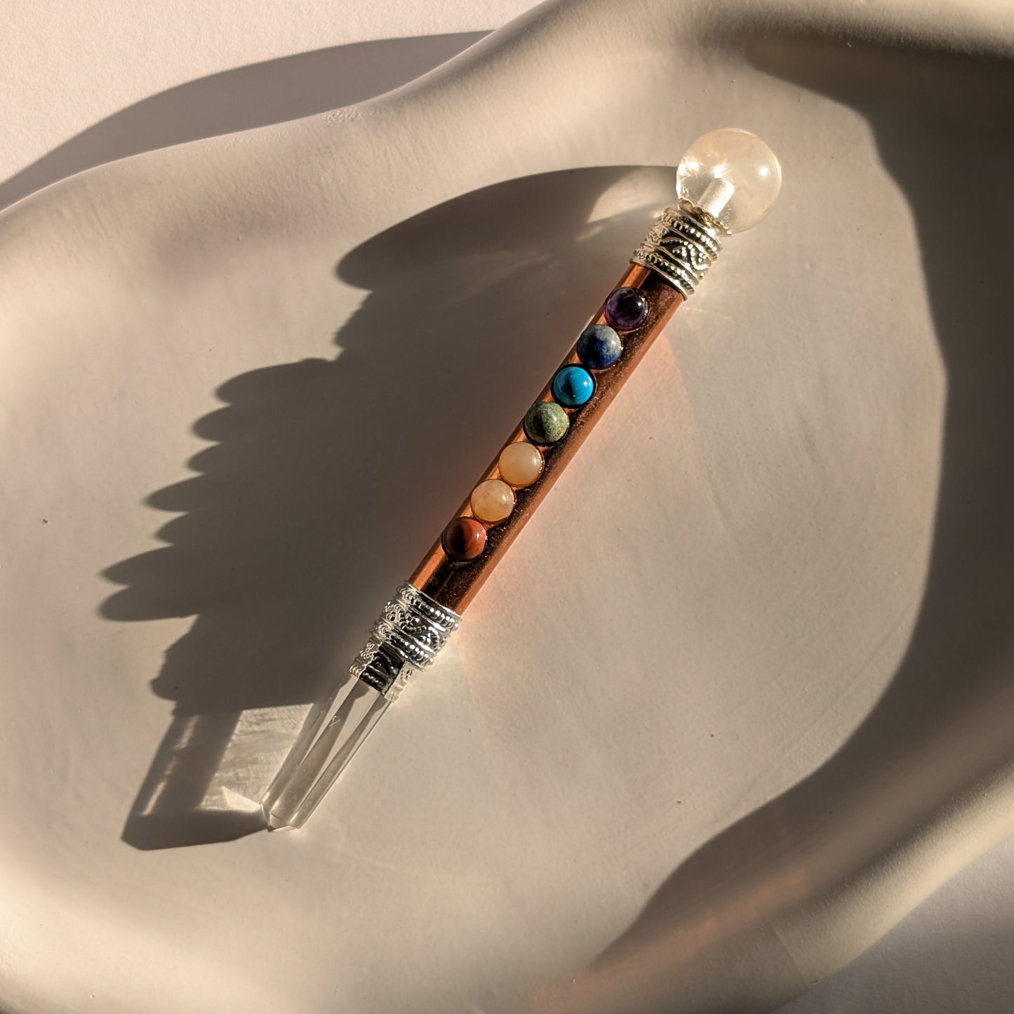 Handgehaltener Chakra-Stab aus leuchtendem Kupfer mit sieben farbigen Edelsteinen und Bergkristall-Spitzen.