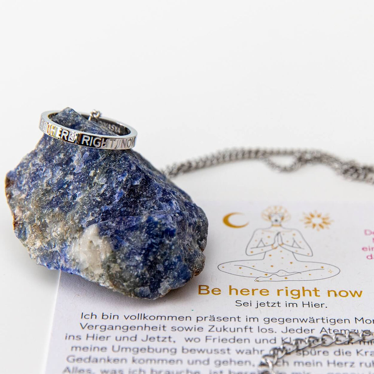 Silberne Kette mit Ring 'Be here right now' auf hellem Hintergrund