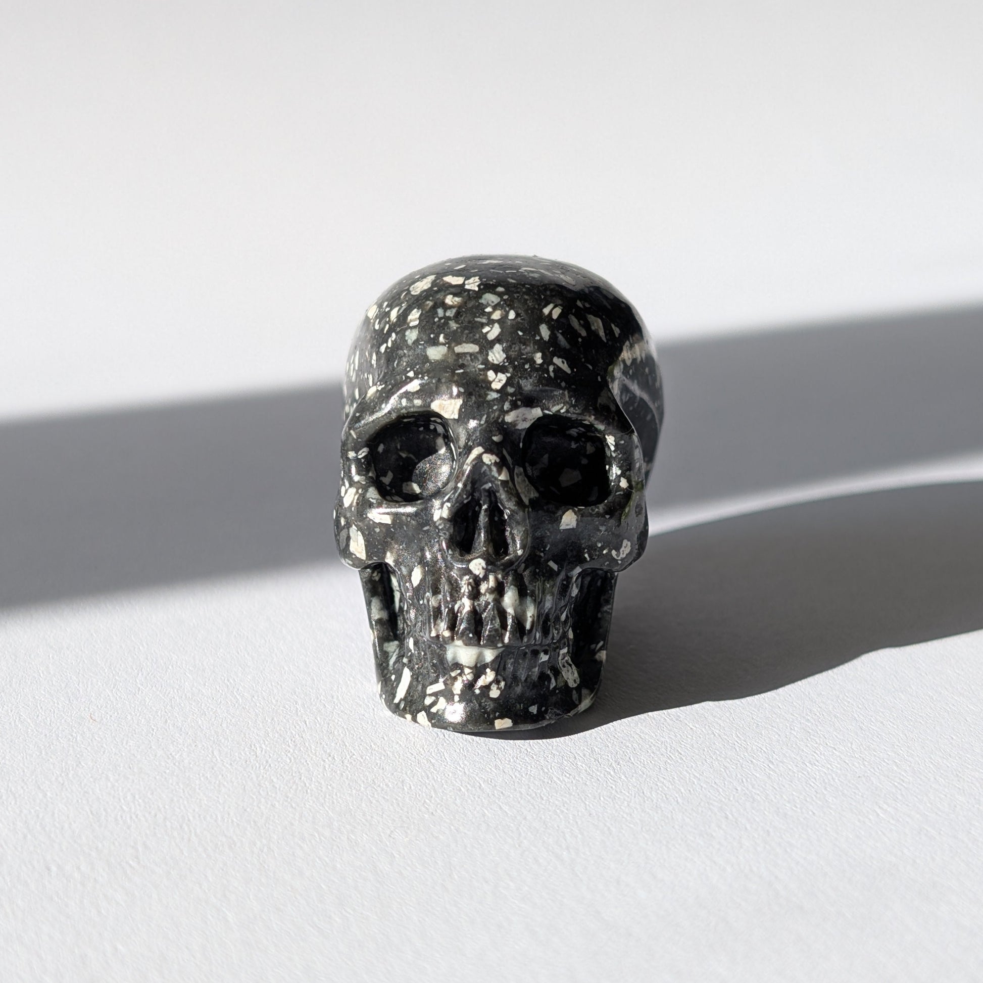 Kleiner Kristallschädel "Blyss" (87g) aus dunkelgrauem Gabbro (Mystic Merlinite) mit hellen Sprenkeln.
