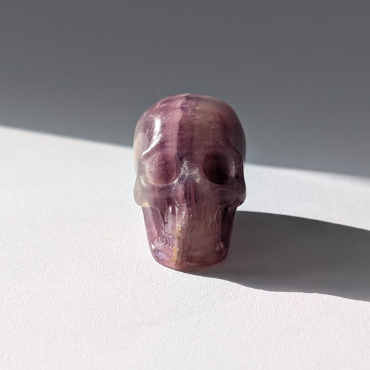 Kleiner Kristallschädel "Boron" (99g) aus klar gebändertem violett-weißem Fluorit.