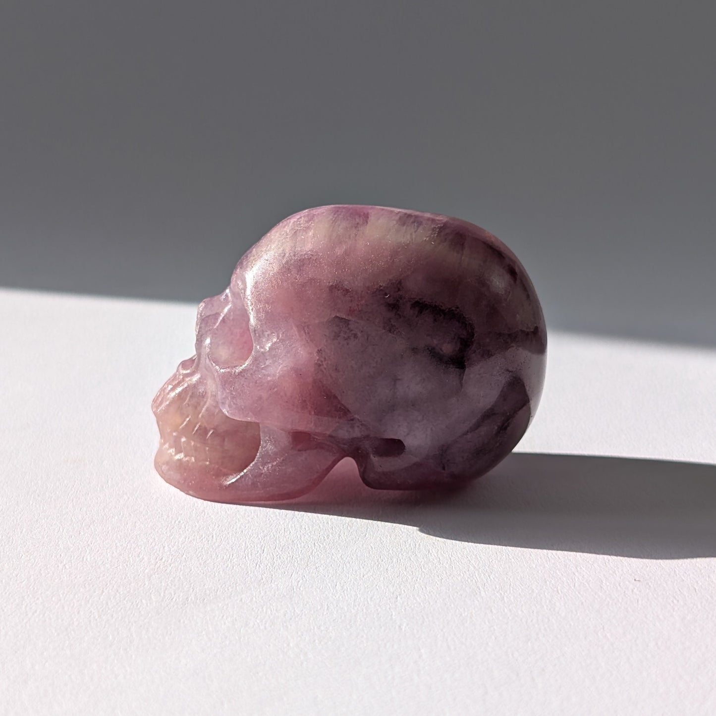 Kleiner Kristallschädel "Boron" (99g) aus klar gebändertem violett-weißem Fluorit.