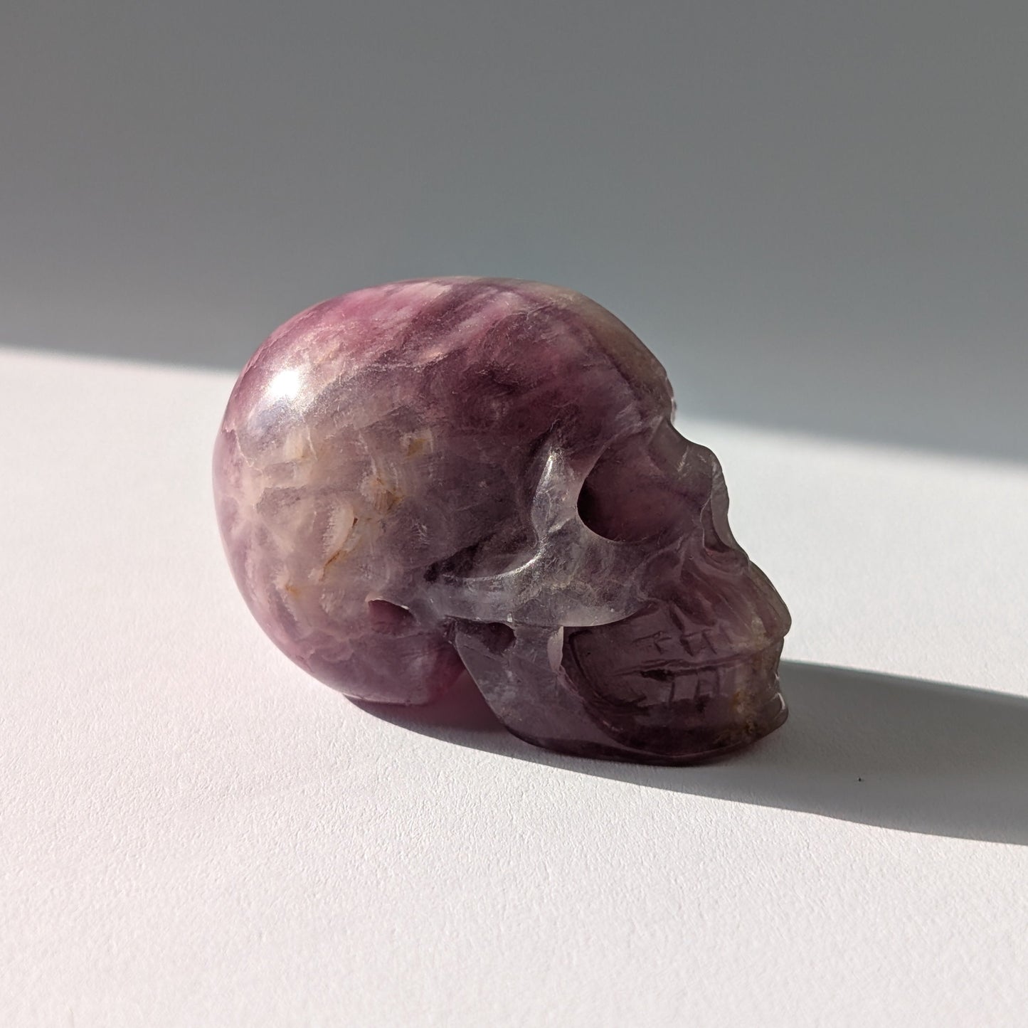 Kleiner Kristallschädel "Boron" (99g) aus klar gebändertem violett-weißem Fluorit.