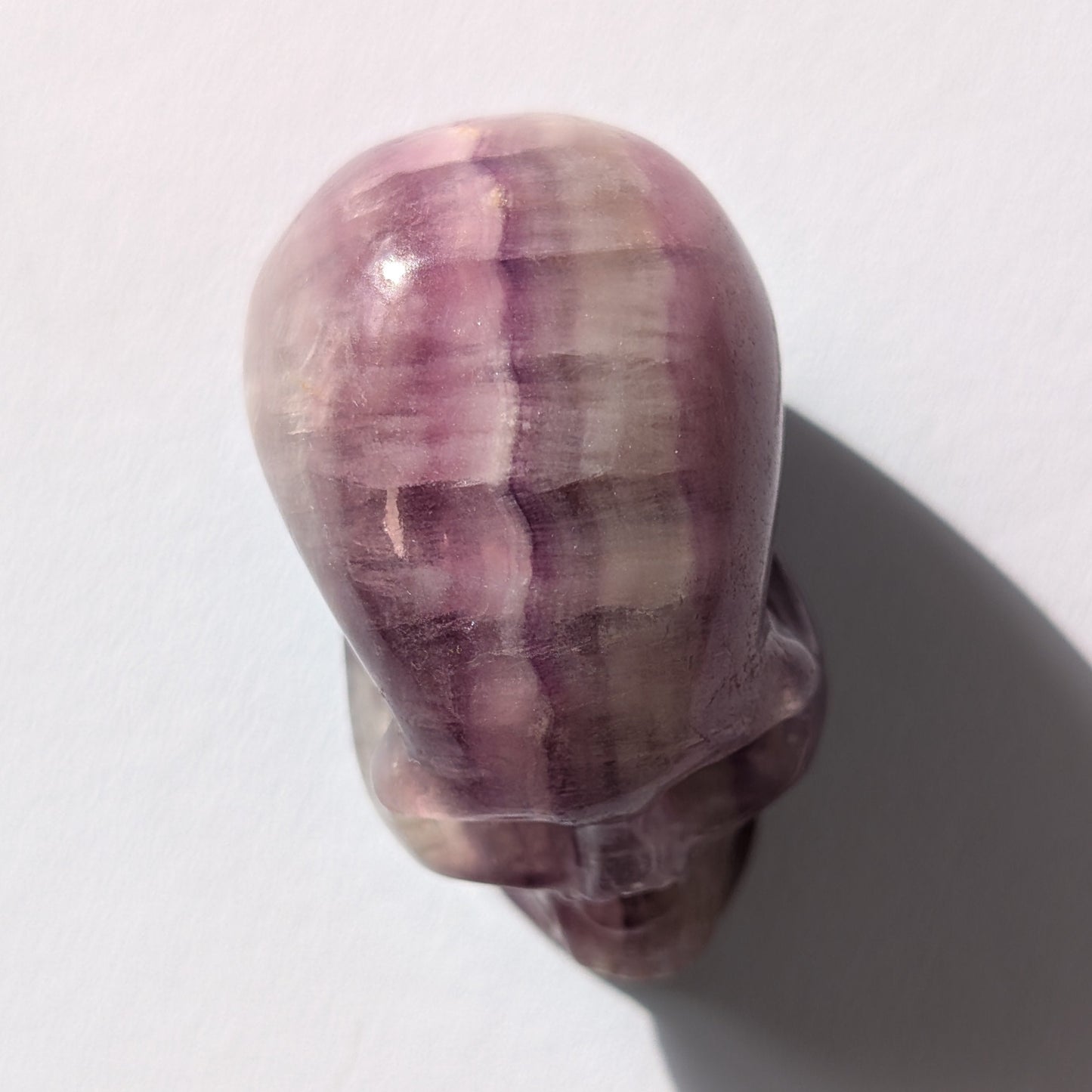 Kleiner Kristallschädel "Boron" (99g) aus klar gebändertem violett-weißem Fluorit.