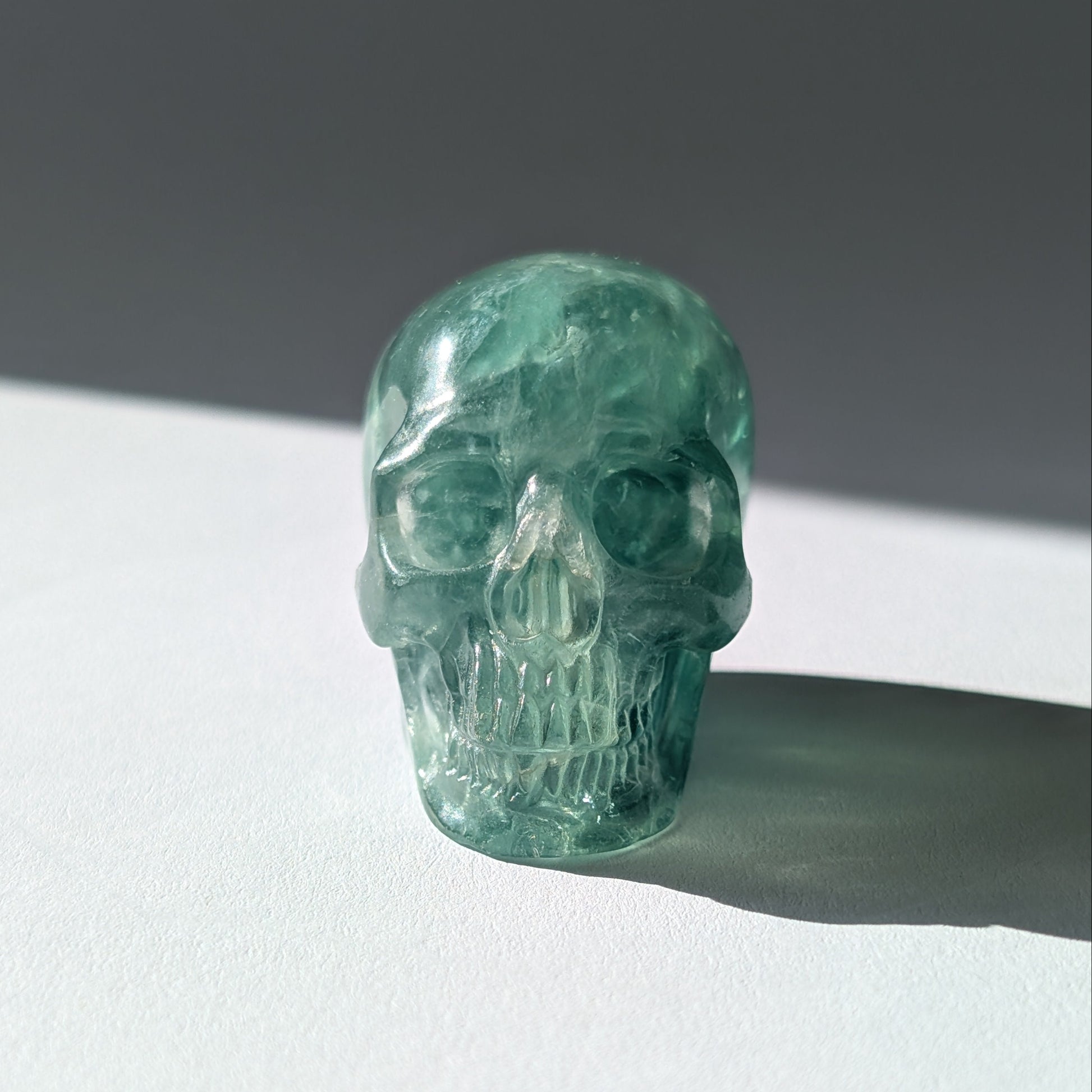 Kleiner Kristallschädel "Buros" (98g) aus klar gebändertem violett-weißem Fluorit.