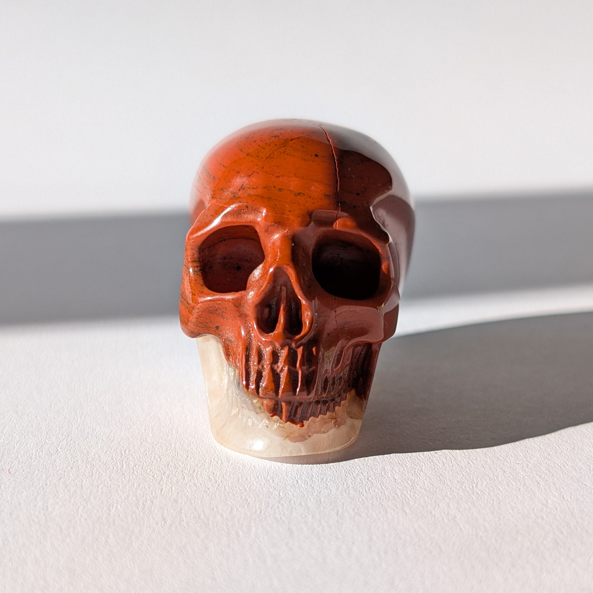 Kleiner Kristallschädel "Edun" (86g), halb aus rotem Jaspis, halb aus hellem Quarz.