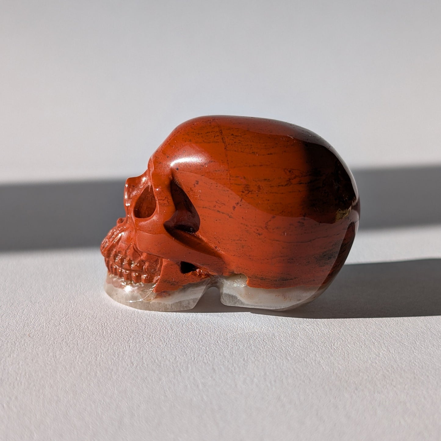 Kleiner Kristallschädel "Edun" (86g), halb aus rotem Jaspis, halb aus hellem Quarz.