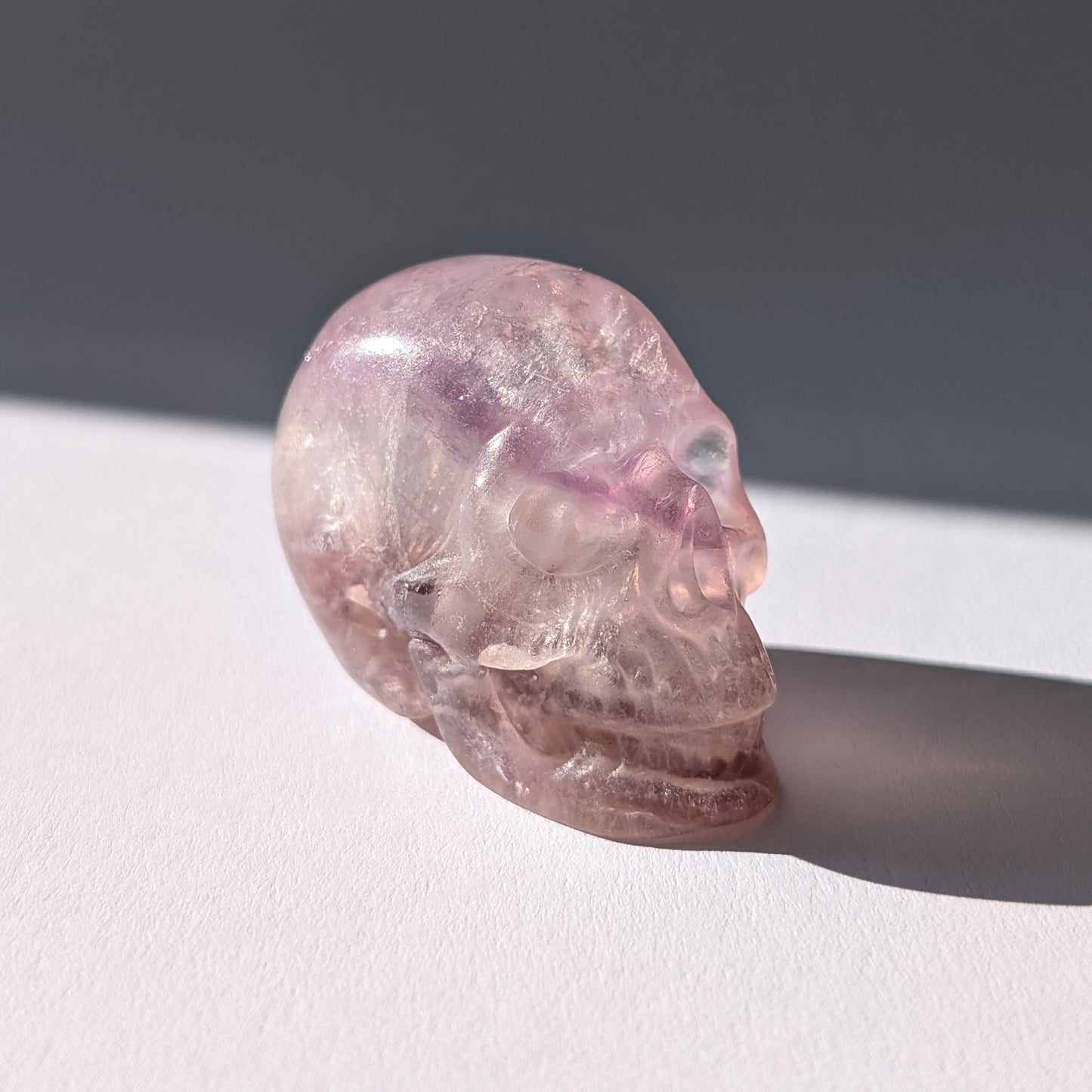 Kleiner Kristallschädel "Nilas" (87g) aus zart rosa-violettem Fluorit im Licht.