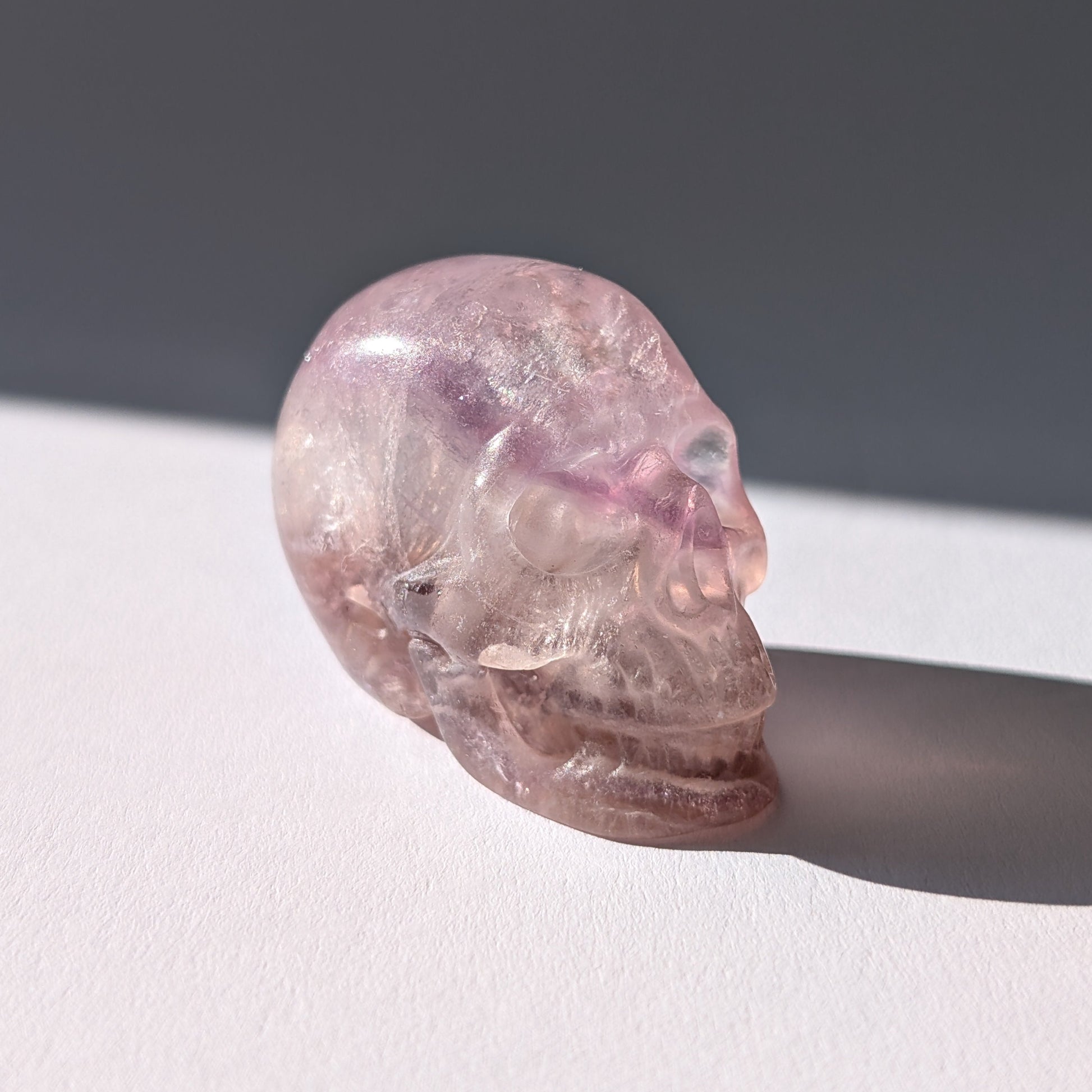 Kleiner Kristallschädel "Nilas" (87g) aus zart rosa-violettem Fluorit im Licht.