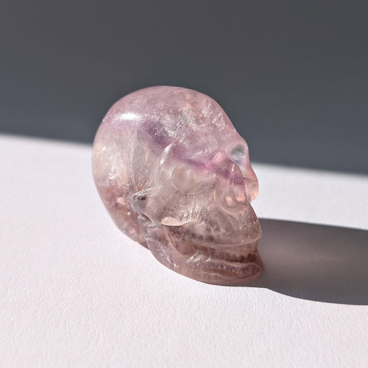 Kleiner Kristallschädel "Nilas" (87g) aus zart rosa-violettem Fluorit im Licht.