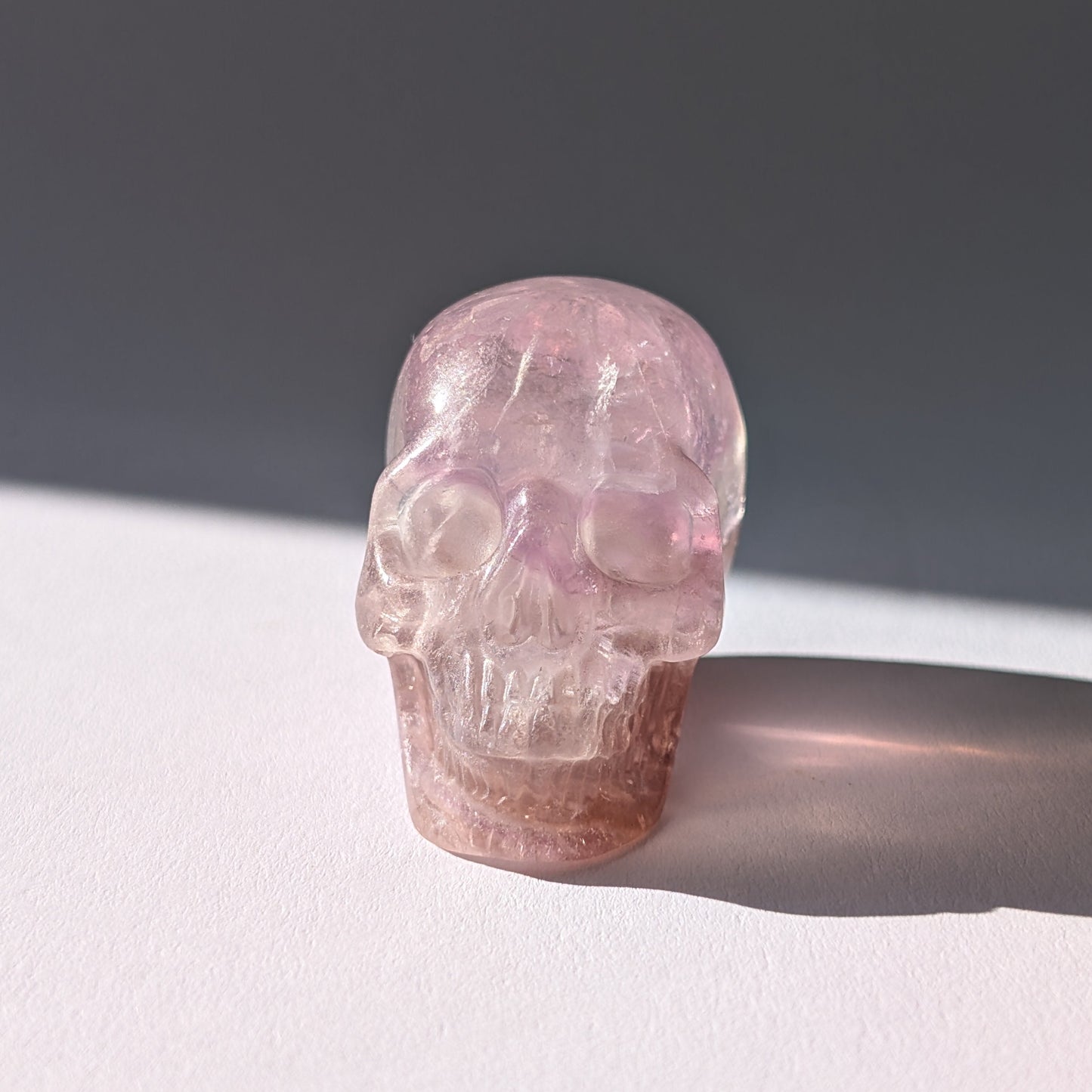 Kleiner Kristallschädel "Nilas" (87g) aus zart rosa-violettem Fluorit im Licht.