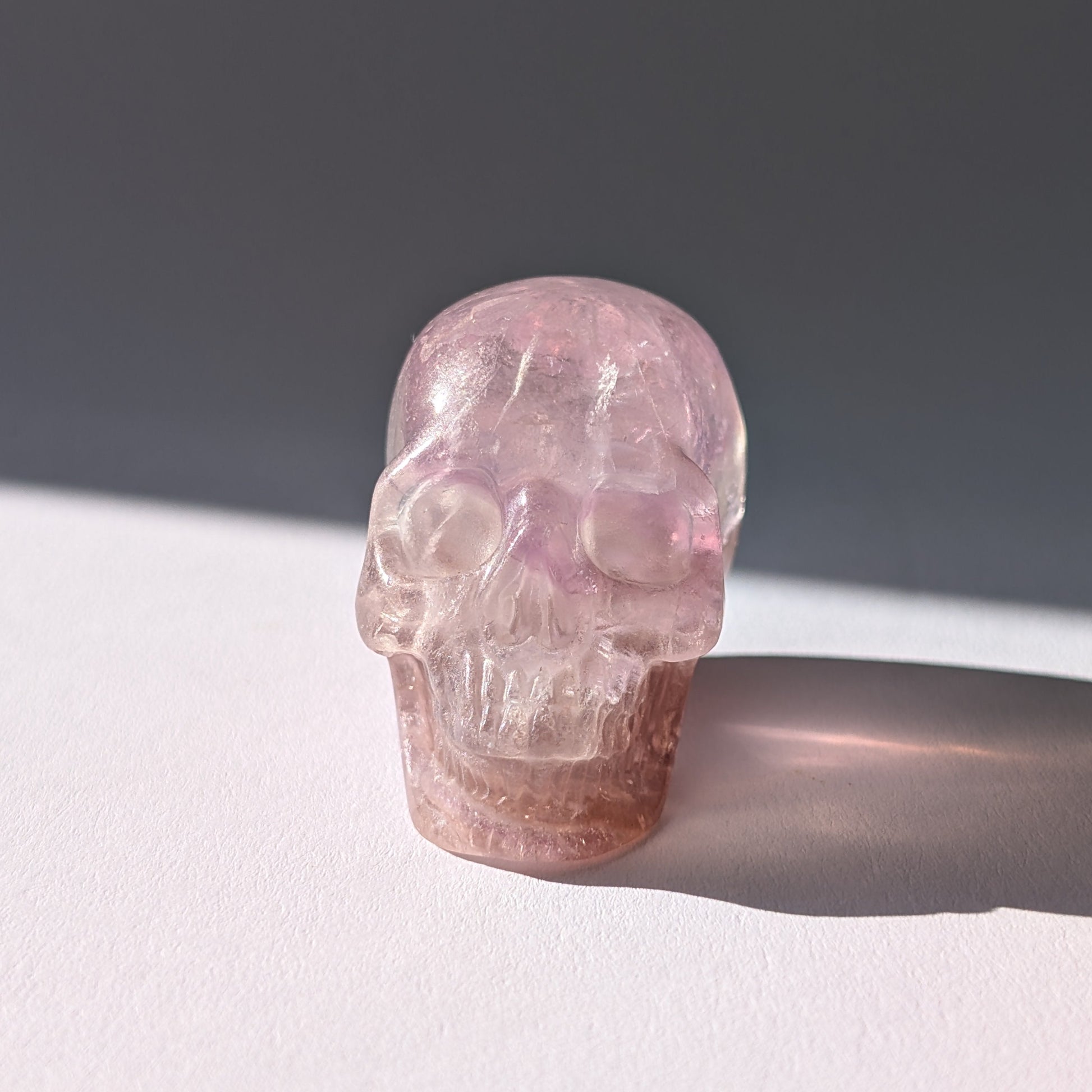 Kleiner Kristallschädel "Nilas" (87g) aus zart rosa-violettem Fluorit im Licht.