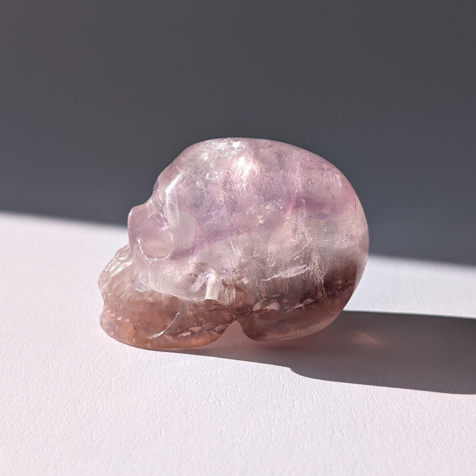 Kleiner Kristallschädel "Nilas" (87g) aus zart rosa-violettem Fluorit im Licht.