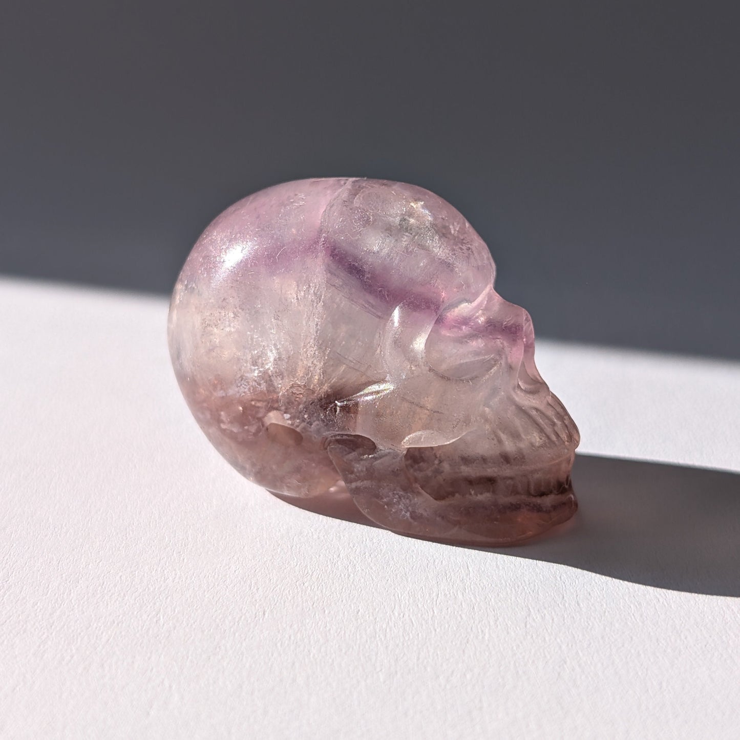 Kleiner Kristallschädel "Nilas" (87g) aus zart rosa-violettem Fluorit im Licht.