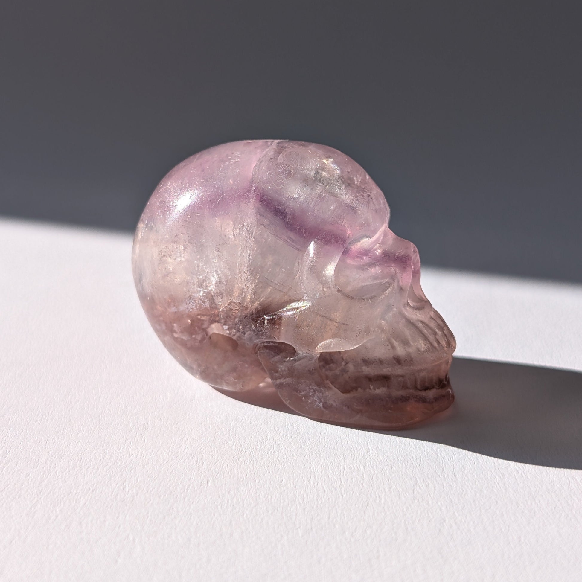Kleiner Kristallschädel "Nilas" (87g) aus zart rosa-violettem Fluorit im Licht.