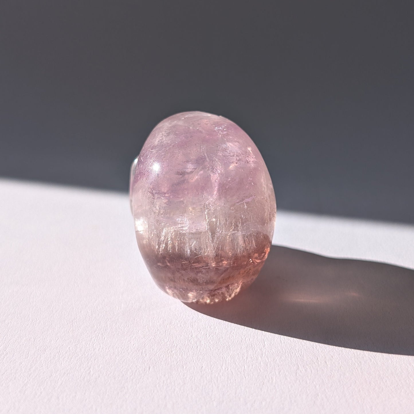 Kleiner Kristallschädel "Nilas" (87g) aus zart rosa-violettem Fluorit im Licht.