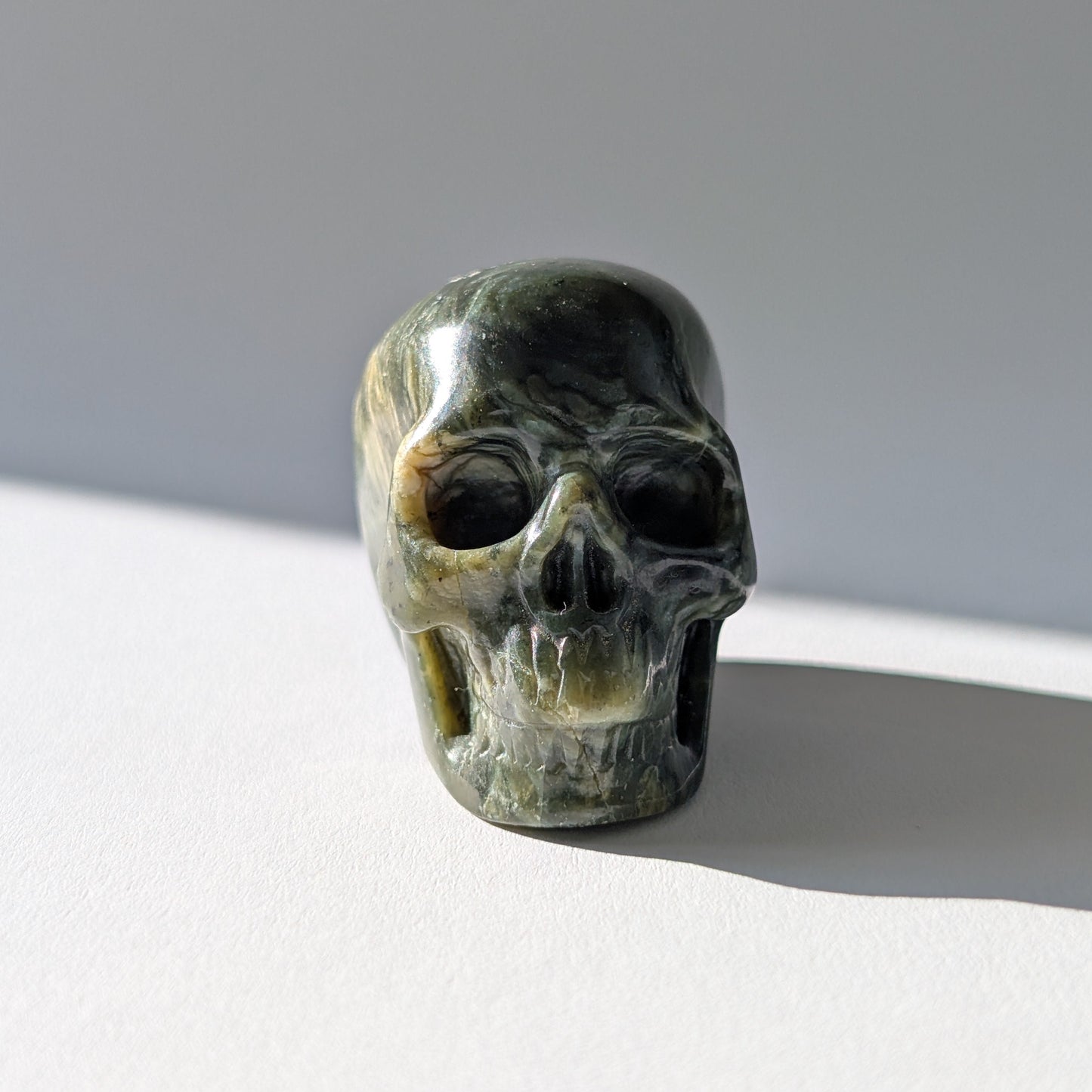 Kleiner Kristallschädel "Obak" (78g) aus dunkelgrün gemustertem Serpentin.