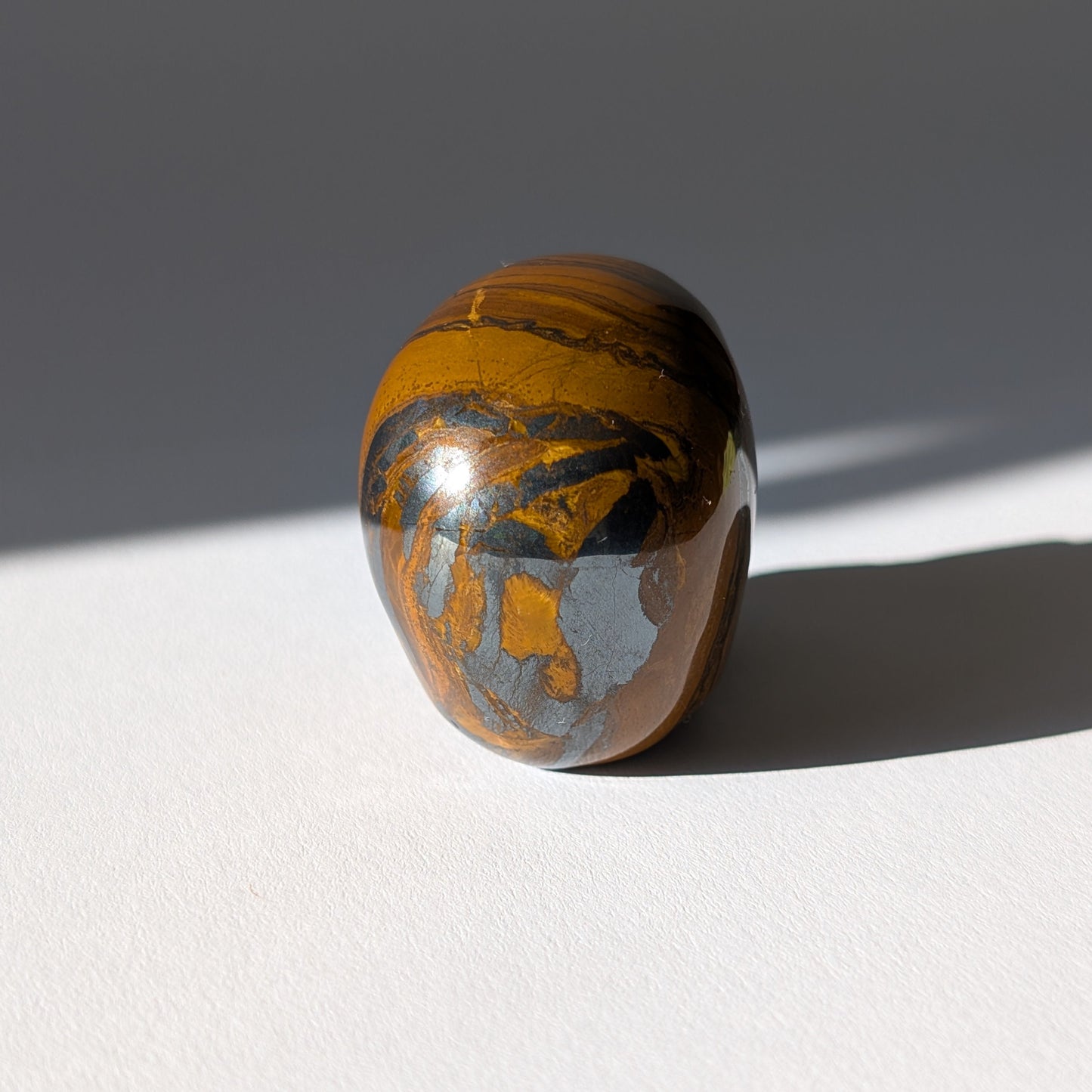 Kleiner Kristallschädel "Rogras" (104g) aus gebändertem Tigereisen mit goldener Chatoyancy.