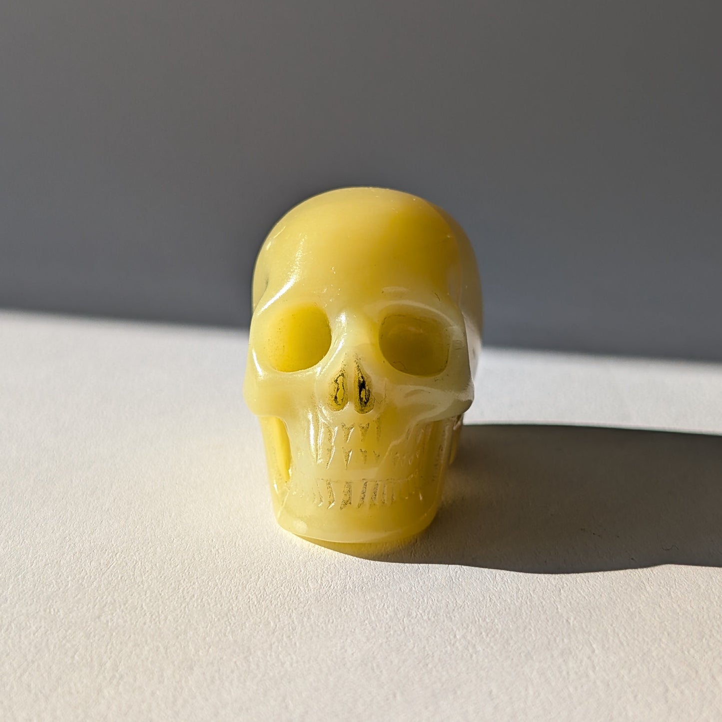 Kleiner Kristallschädel "Sentos" (78g) aus blassgrün-gelbem Jadeit im Licht.