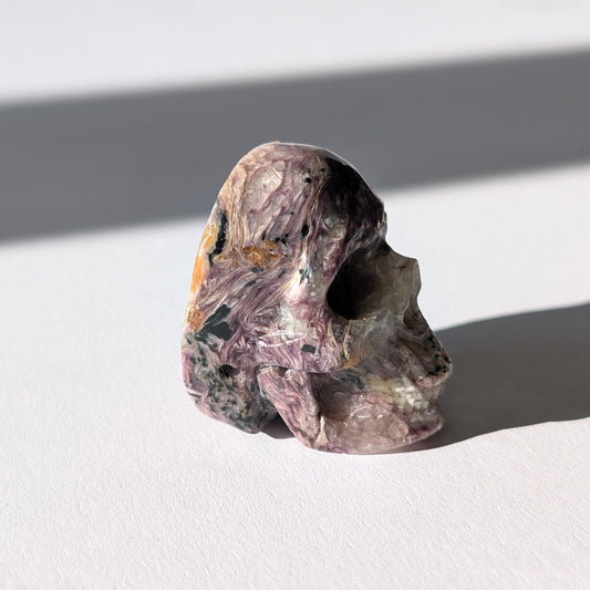Kleiner Kristallschädel "Veykor" (51g) aus violettem Charoit mit seidigen Wirbeln.
