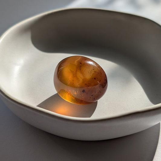 Kleiner, ergonomischer Bicolor-Bernstein 'Der goldene Funke' mit juwelenartiger Klarheit und einem Farbverlauf von Cognac zu Gold.