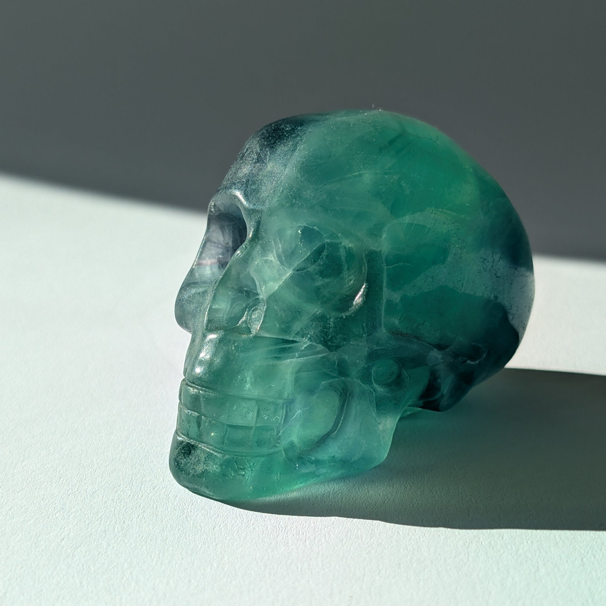 Kristallschädel "Guilin" (338g) aus leuchtend grünem, klarem Fluorit im Licht.