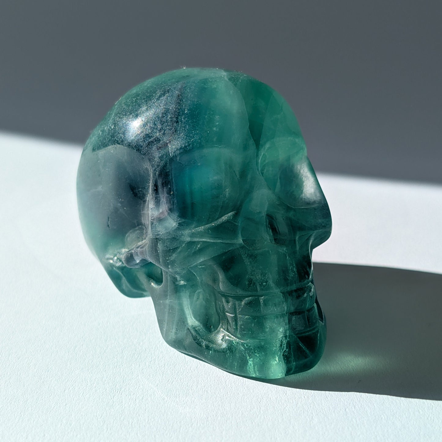 Kristallschädel "Guilin" (338g) aus leuchtend grünem, klarem Fluorit im Licht.