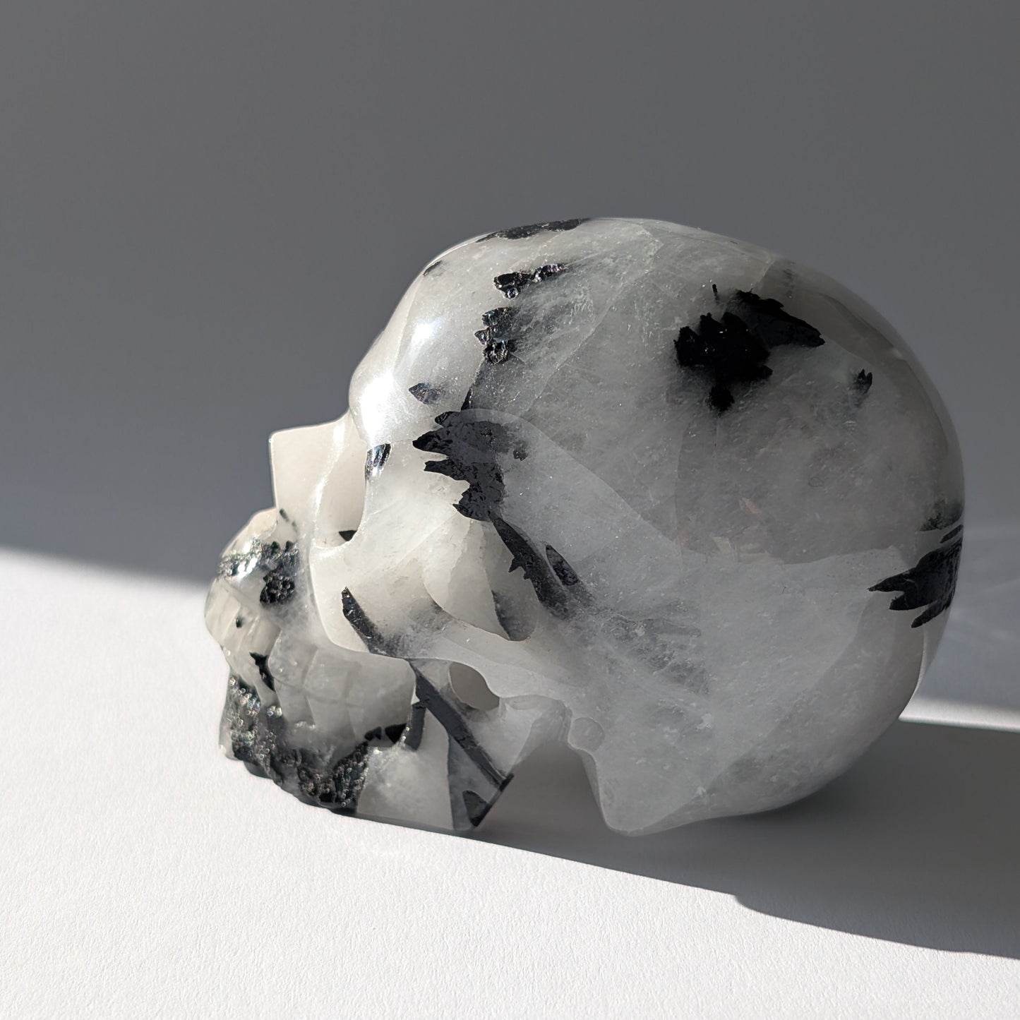 Kristallschädel "Hokan" (436g) aus klarem Quarz mit schwarzen Turmalin-Nadeln.