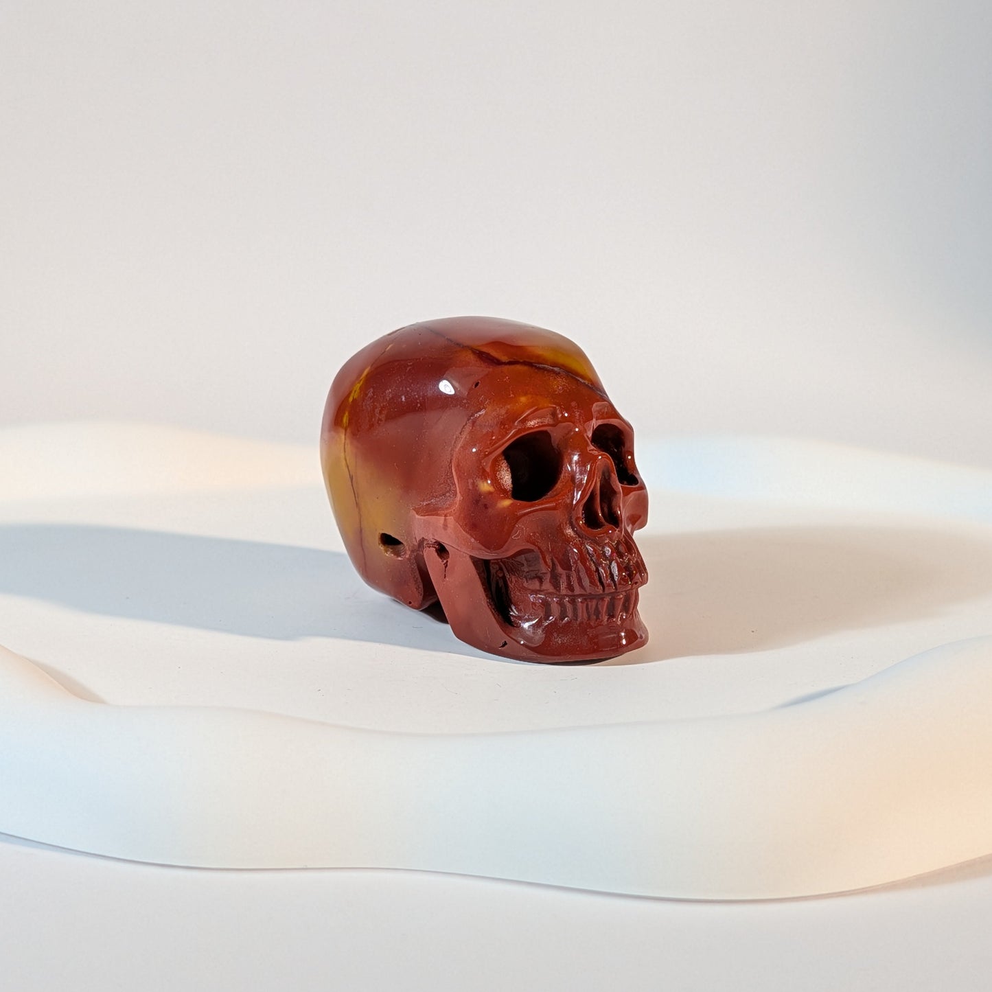 Kristallschädel Sandor aus tiefrotem, erdigem Jaspis 89g mit natürlichen, hellen Rissen im kontrastreichen Licht