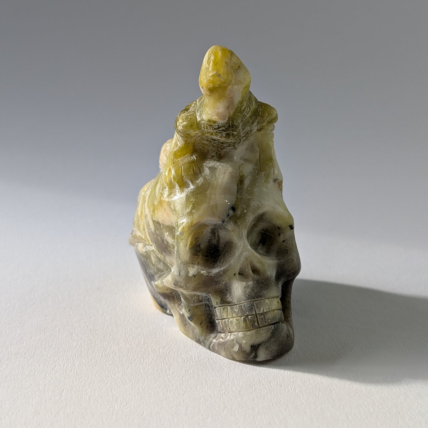 Kristallschädel "Theuth" (140g) aus Serpentin mit einer geschnitzten Eidechse auf dem Kopf.