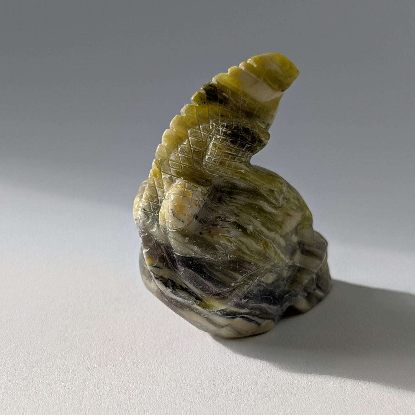 Kristallschädel "Theuth" (140g) aus Serpentin mit einer geschnitzten Eidechse auf dem Kopf.