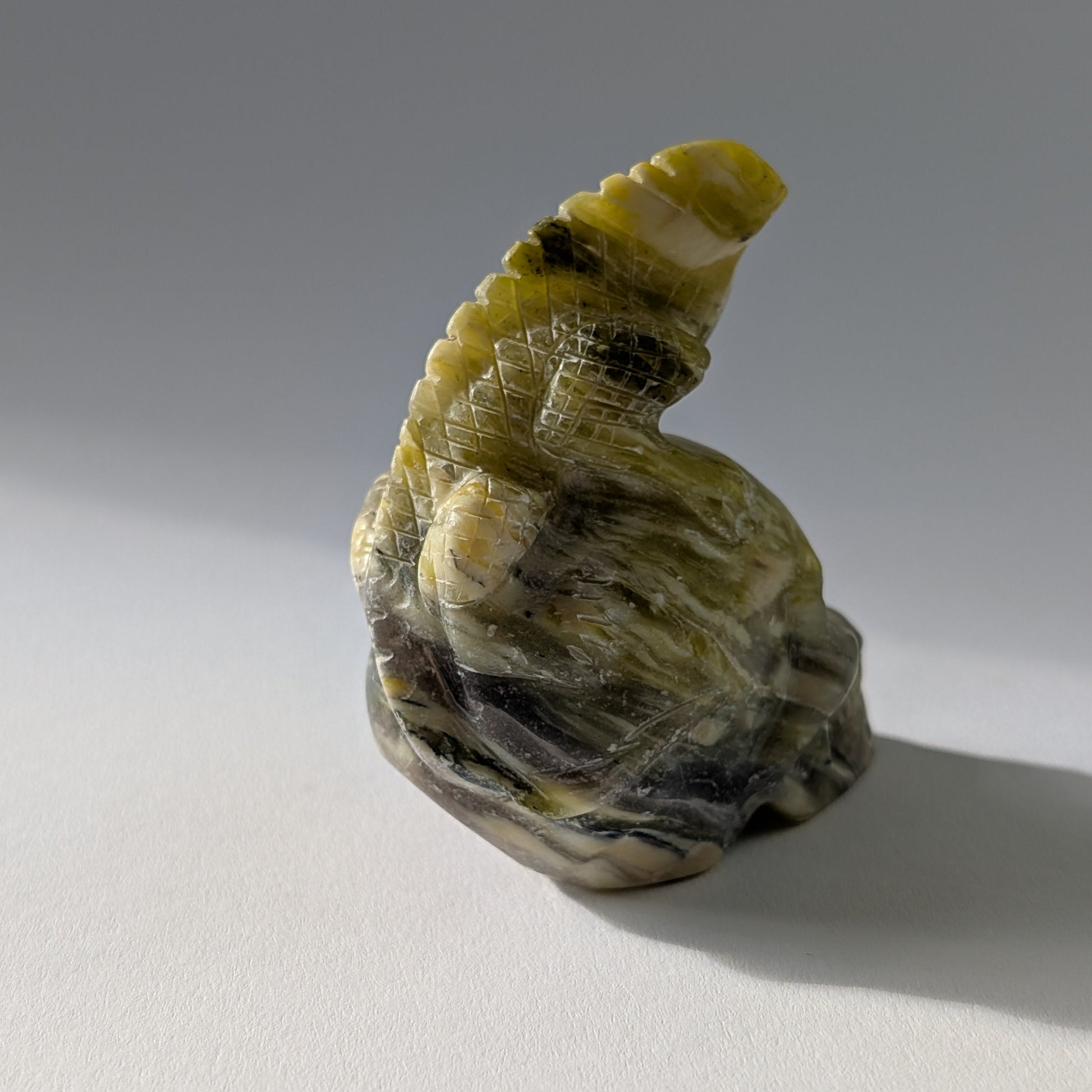 Kristallschädel "Theuth" (140g) aus Serpentin mit einer geschnitzten Eidechse auf dem Kopf.