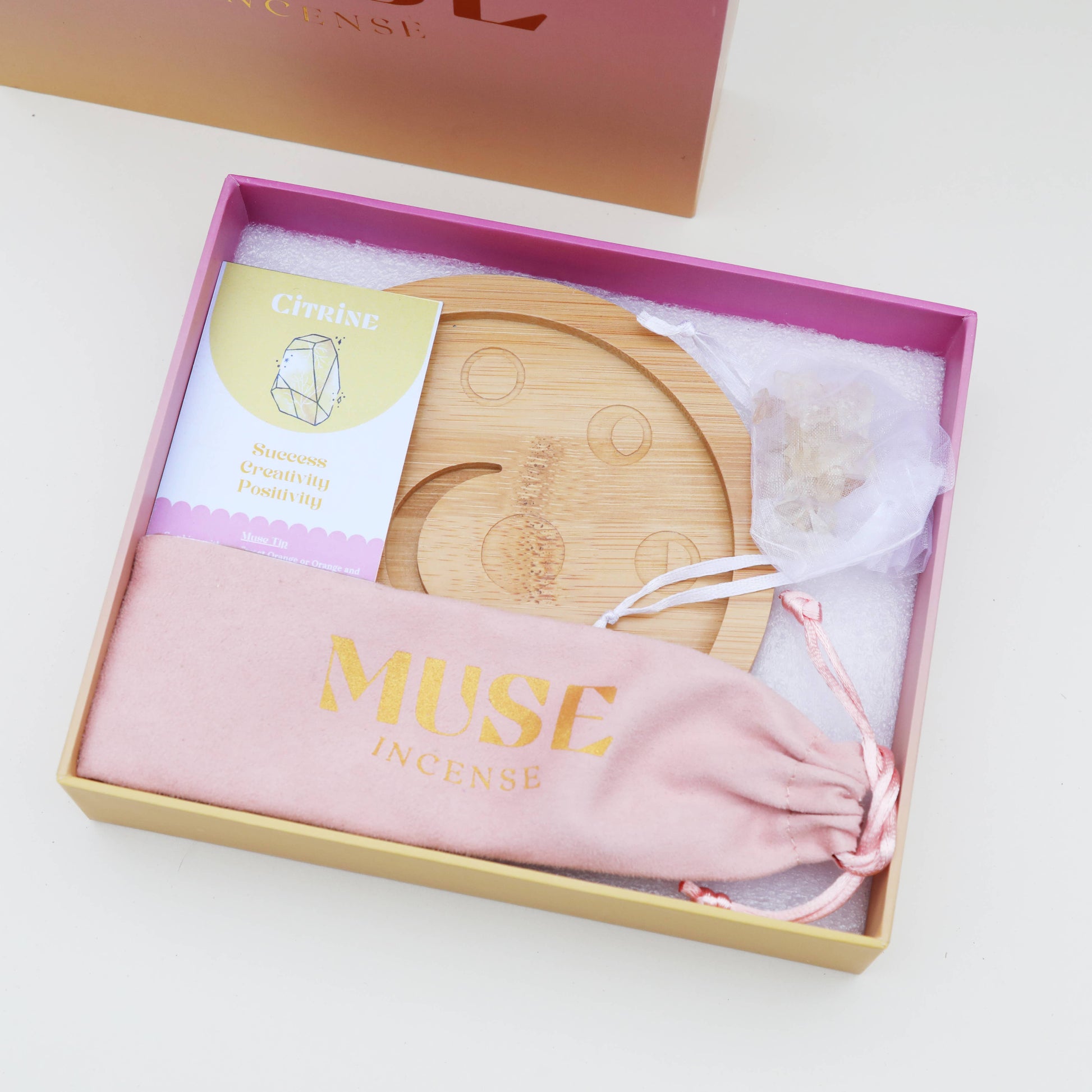 Mondphasen-Kristall-Räucherschale aus Bambus, gefüllt mit grünen Fluorit-Kristallchips, in einer rosa-orangen Geschenkbox von The Golden Altar.