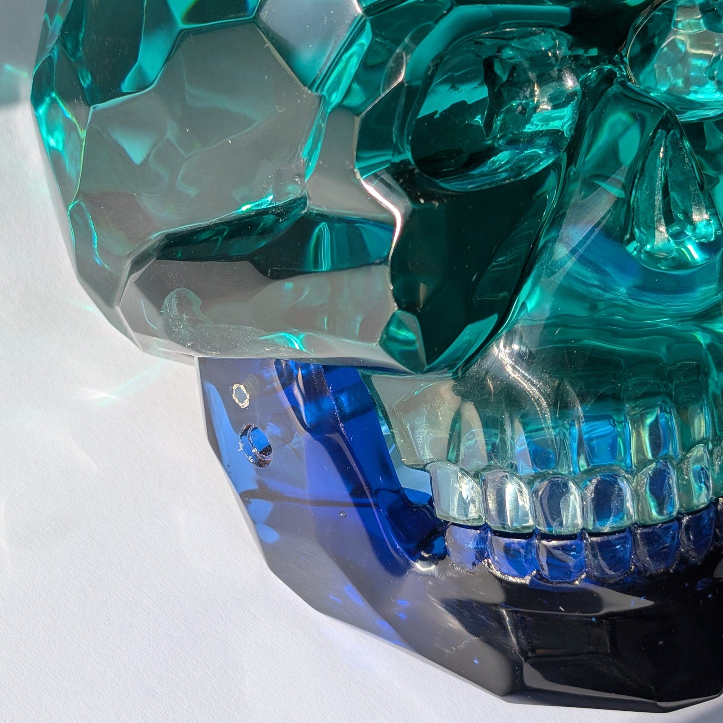 Monumentaler Kristallschädel (7.5kg) aus facettiertem blaugrünem Glas mit beweglichem Unterkiefer im Lichtspiel.