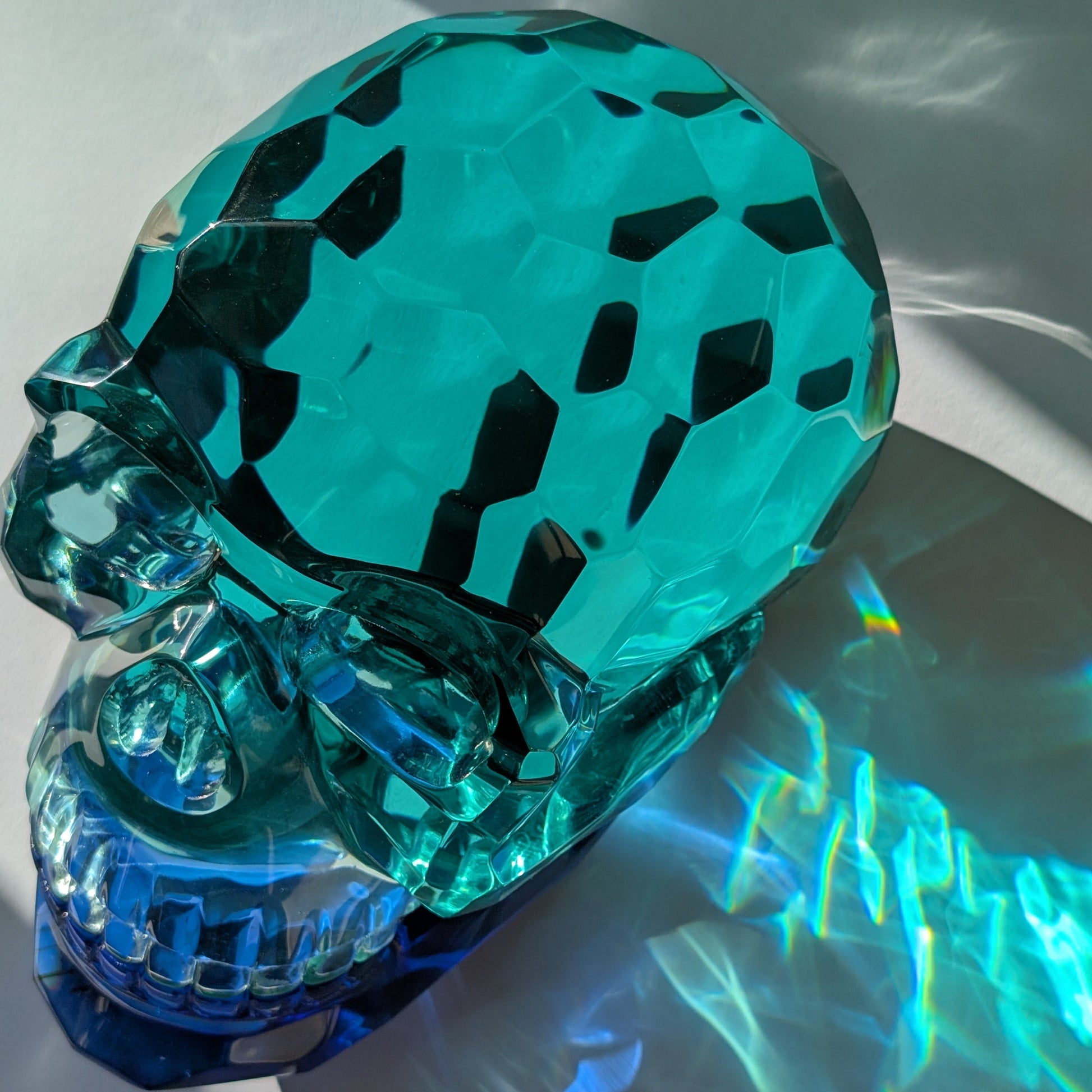 Monumentaler Kristallschädel (7.5kg) aus facettiertem blaugrünem Glas mit beweglichem Unterkiefer im Lichtspiel.