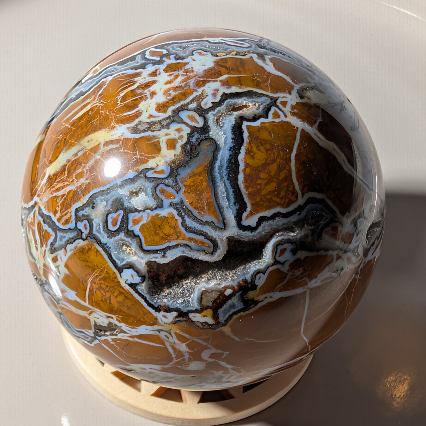 Polierte Drusenachat Kugel in Nahaufnahme mit offener Kristall-Geode und goldgelber Bänderung