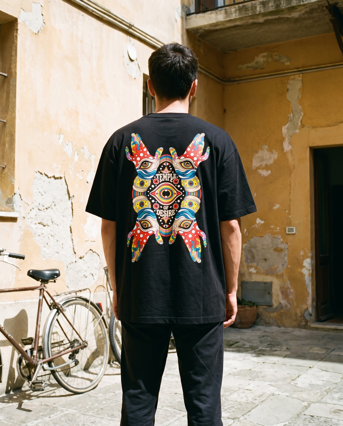 Hände — Sehen: schwarzes Oversized-T-Shirt mit Rückenprint, getragen.