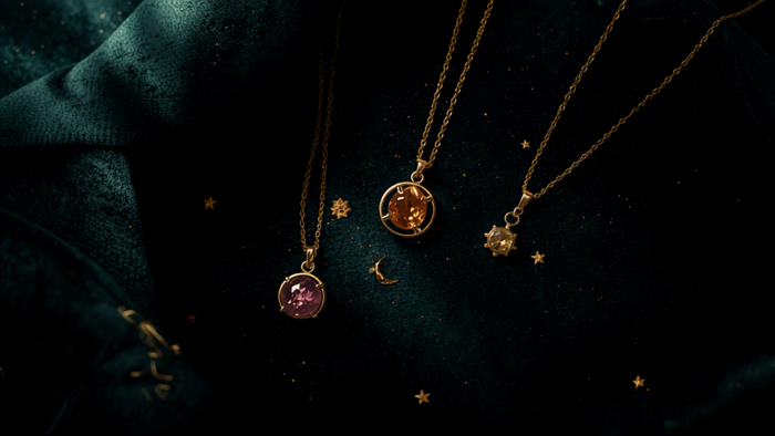 Spiritueller Schmuck: goldene Halsketten mit Amethyst, Citrin und Bernstein auf dunklem Samt