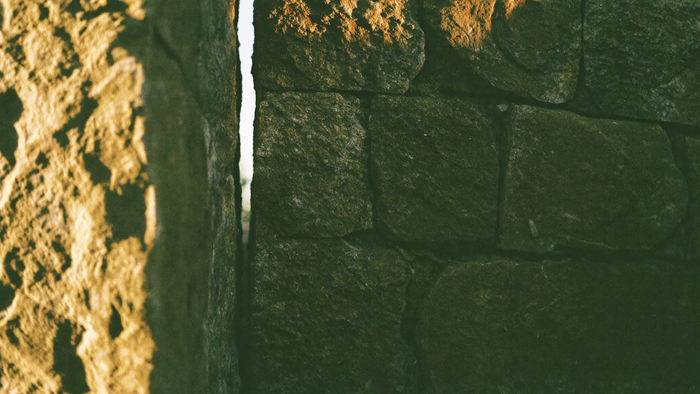 Sonnenbeschienene Spalte in einer alten Steinmauer — das Versteck, aus dem die Eidechse ins Licht zurückkehrt