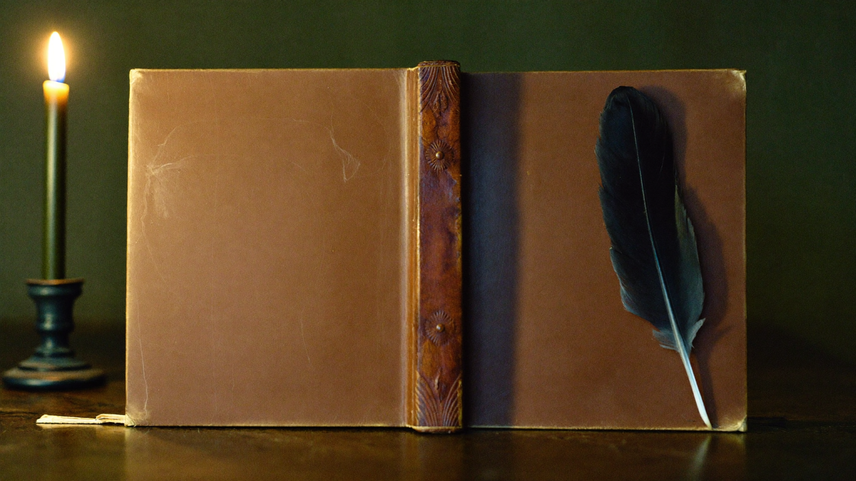 Ein altes ledergebundenes Buch mit glattem Einband liegt aufgeschlagen auf einer dunklen Steinfläche, daneben eine schwarze Rabenfeder und eine brennende Kerze vor dunkelgrüner Wand.