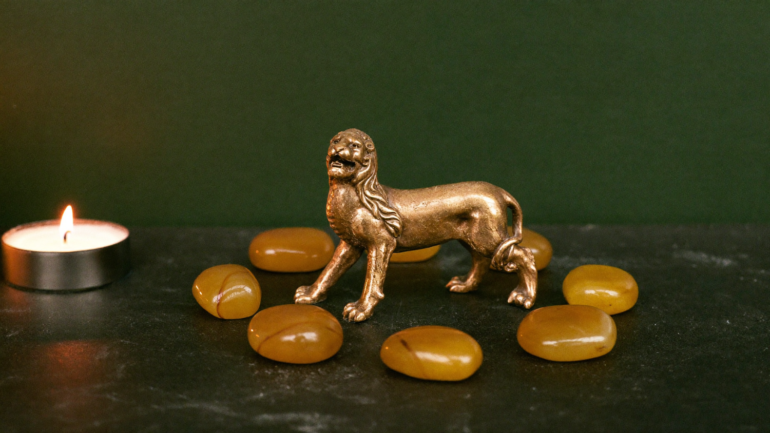 Messing-Löwenfigur umringt von acht Bernsteinen im Kerzenlicht — Symbolbild für das Löwentor am 8.8.2026