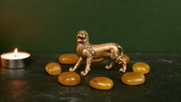 Messing-Löwenfigur umringt von acht Bernsteinen im Kerzenlicht — Symbolbild für das Löwentor am 8.8.2026