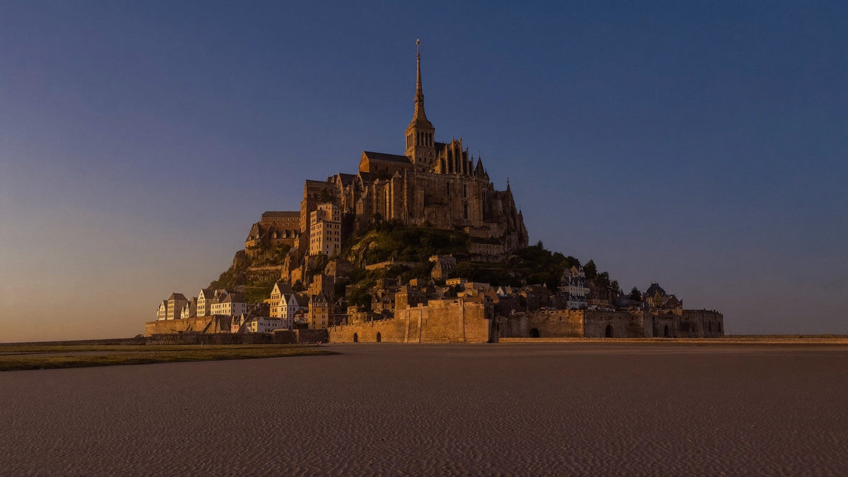 Mont-Saint-Michel in der Abenddämmerung: Gezeiteninsel mit gotischer Abtei und Turmspitze über geriffeltem Watt