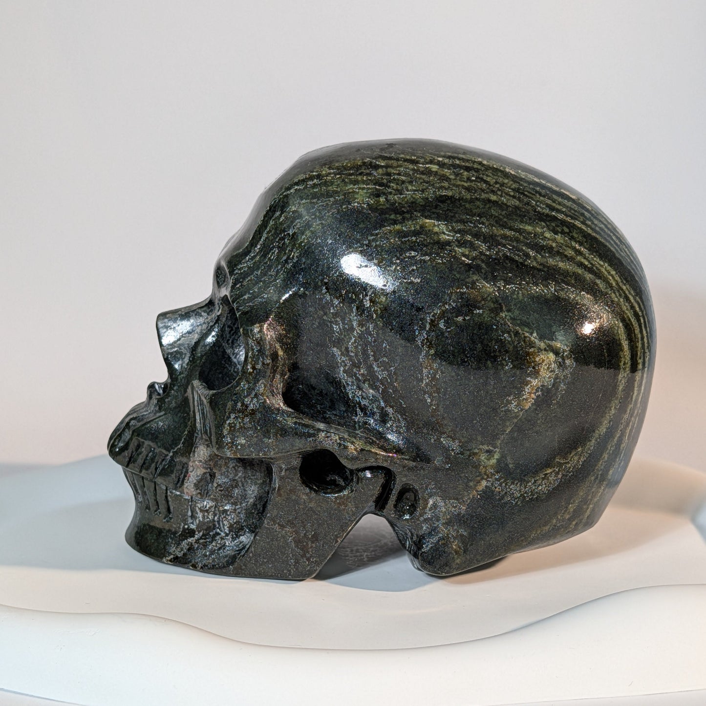 Gewaltiger Kristallschädel Tantaro aus dunkelrotem und braunem Serpentin, gezeichnet von scharfen, dunklen Gesteinsadern