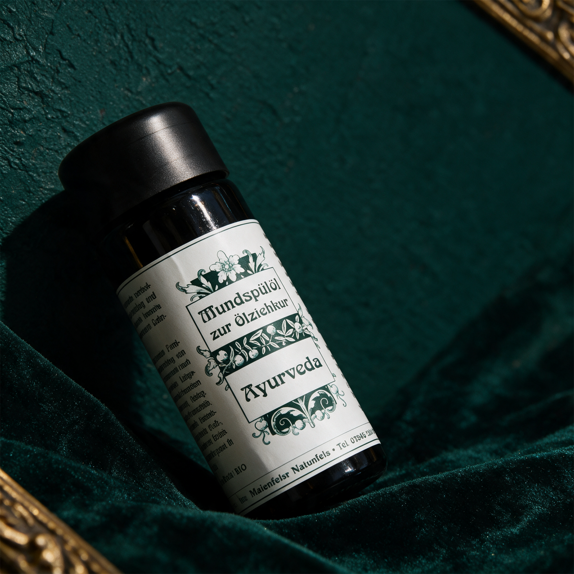 Ayurveda Mundspülöl von der Seite vor tiefgrünem Hintergrund
