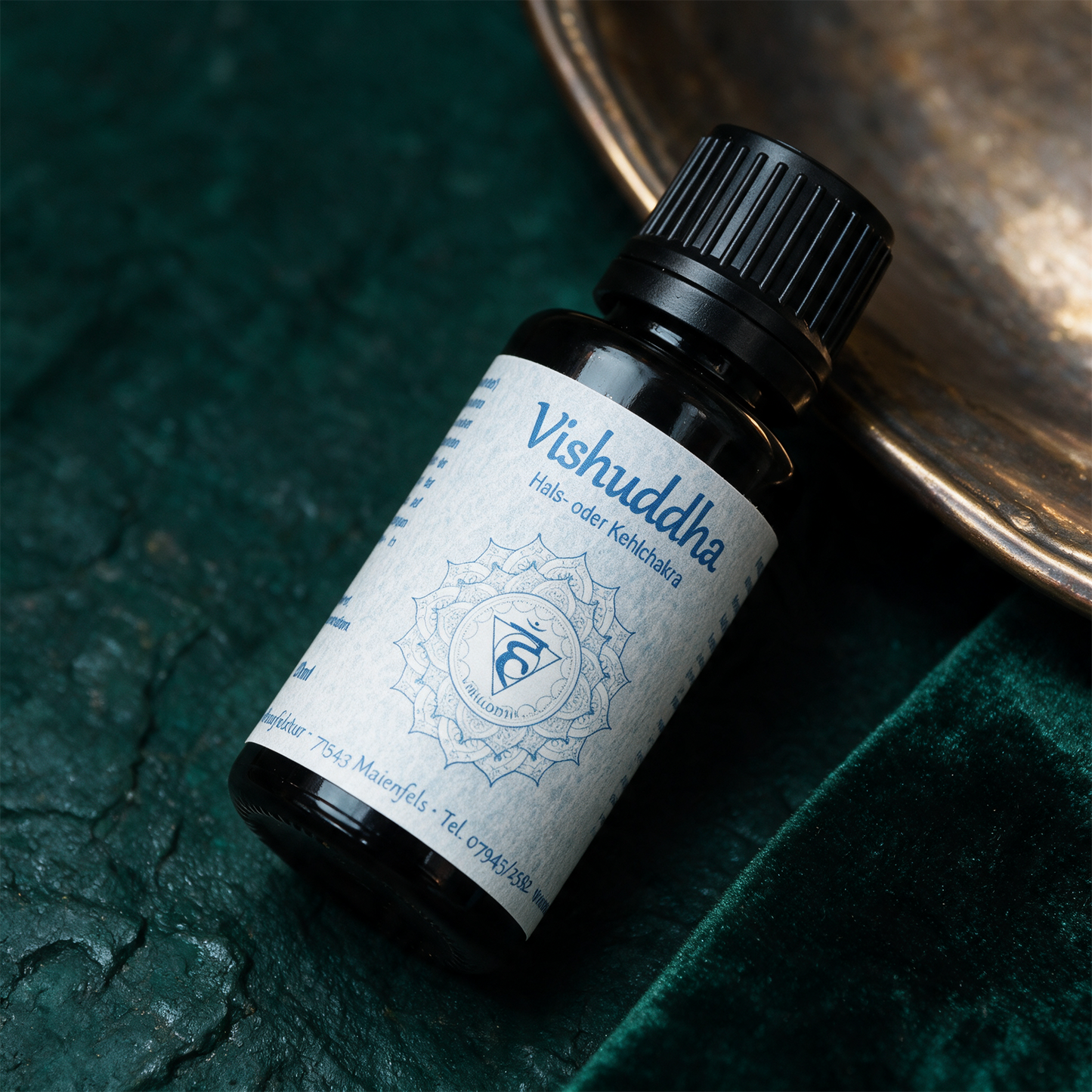 Vishuddha Chakraöl neben Aquamarin und Türkis auf dunklem Stein