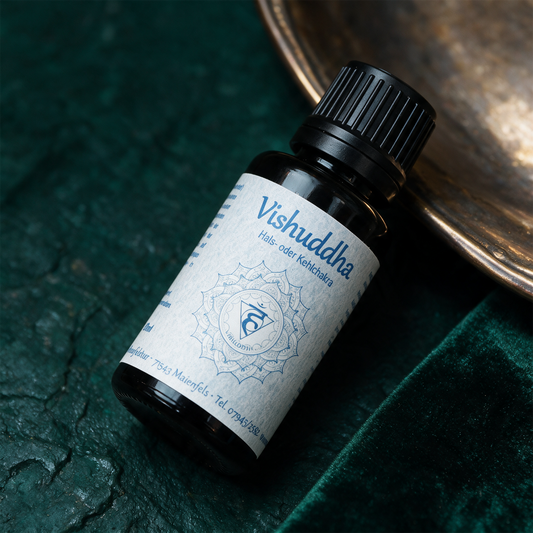 Vishuddha Chakraöl neben Aquamarin und Türkis auf dunklem Stein