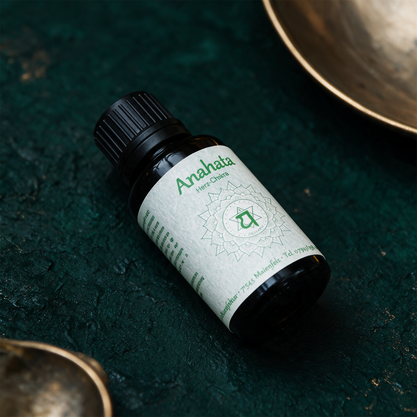 Anahata Chakraöl neben Rosenquarz und Jade auf dunklem Stein
