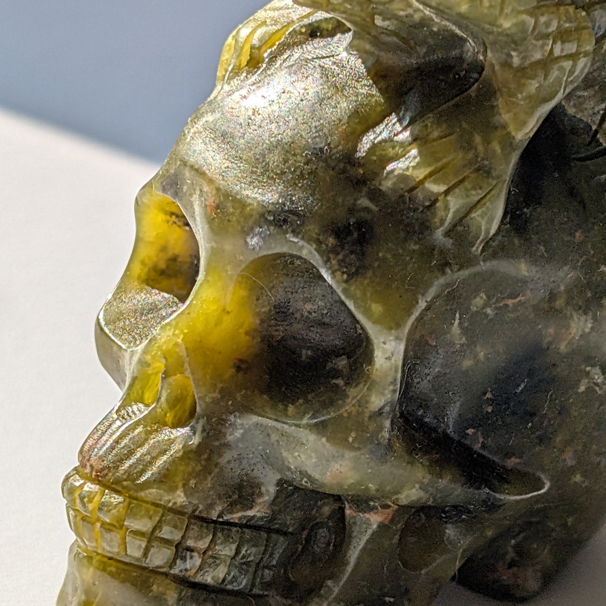 Ein 168g schwerer, handgeschnitzter Kristallschädel 'Veratha' aus grünem Serpentin, mit einer detailreichen Kobra, die sich auf seinem Scheitel aufrichtet.